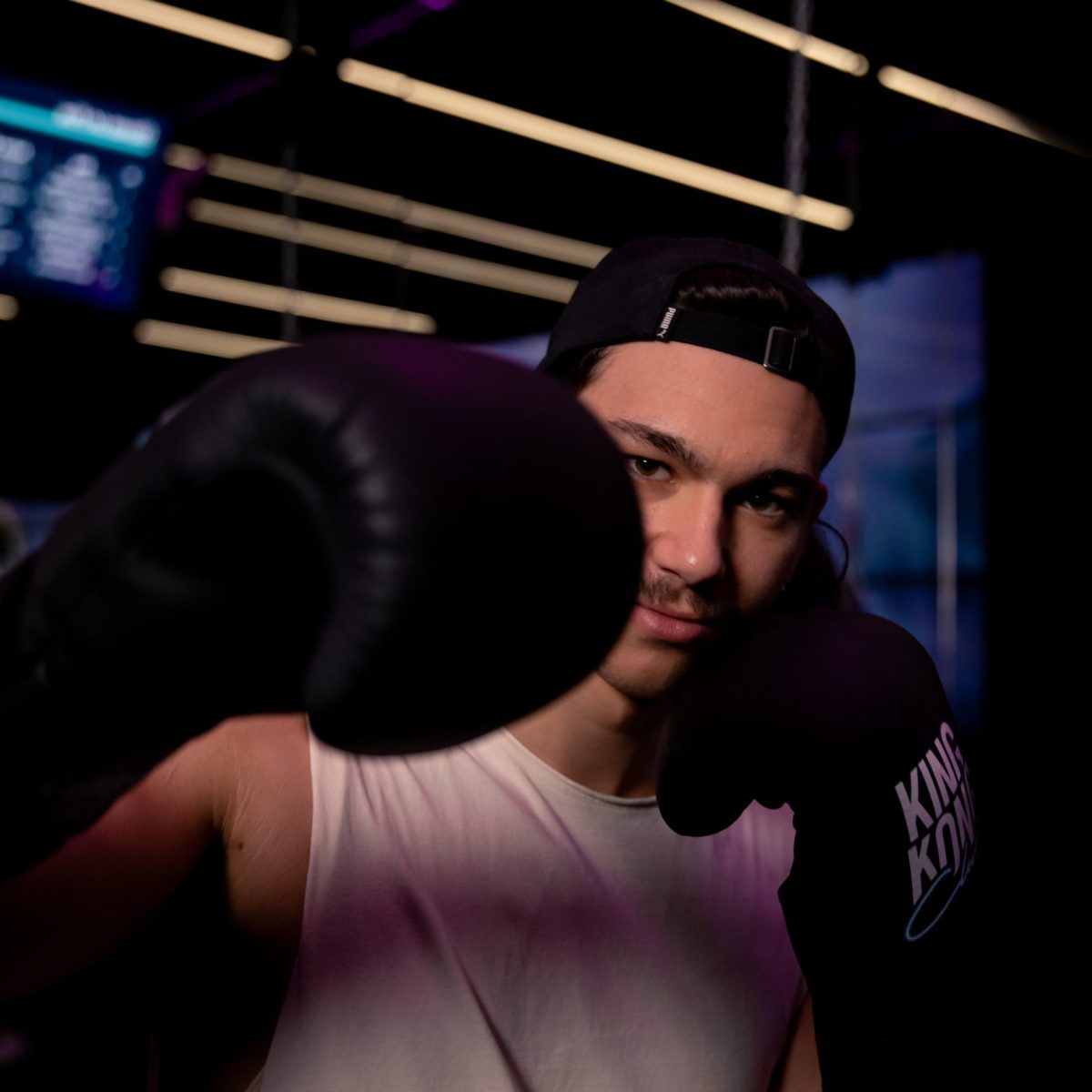 Junger Mann der Boxbewegungen macht mit Boxhandschuhen.