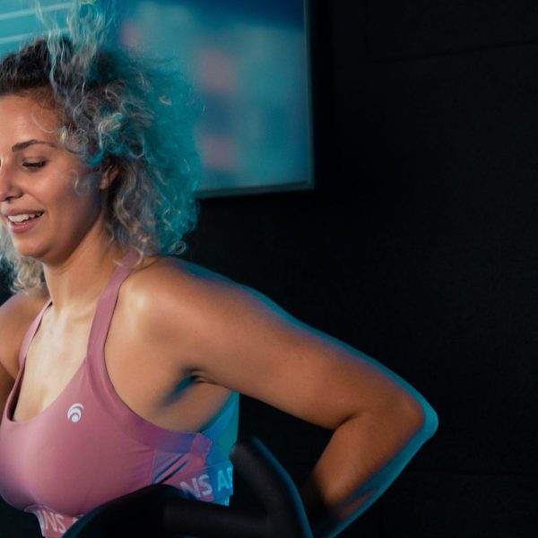 Junge Frau, die im Fitnessstudio Rad fährt.