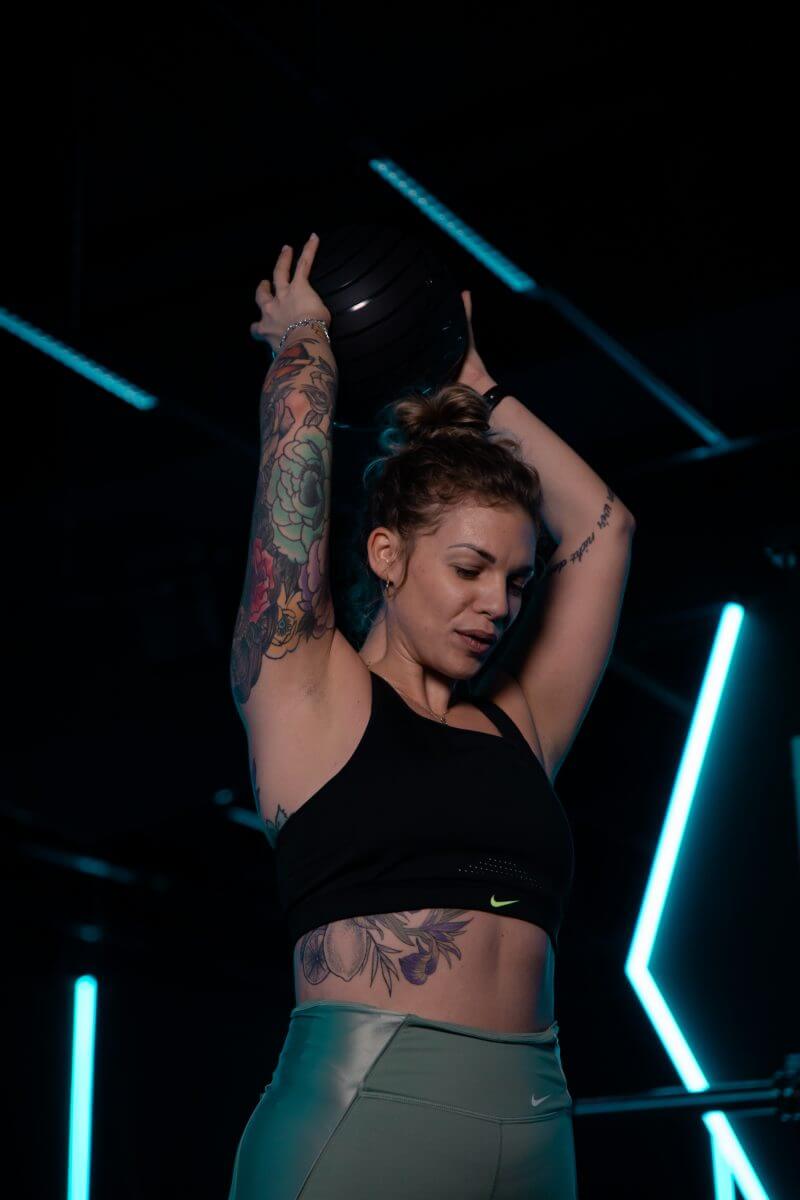 Junge Frau hebt Medizinball beim Training im Kong Kong Club