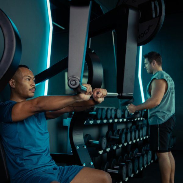 Zwei junge Männer die mit Hanteln trainieren.