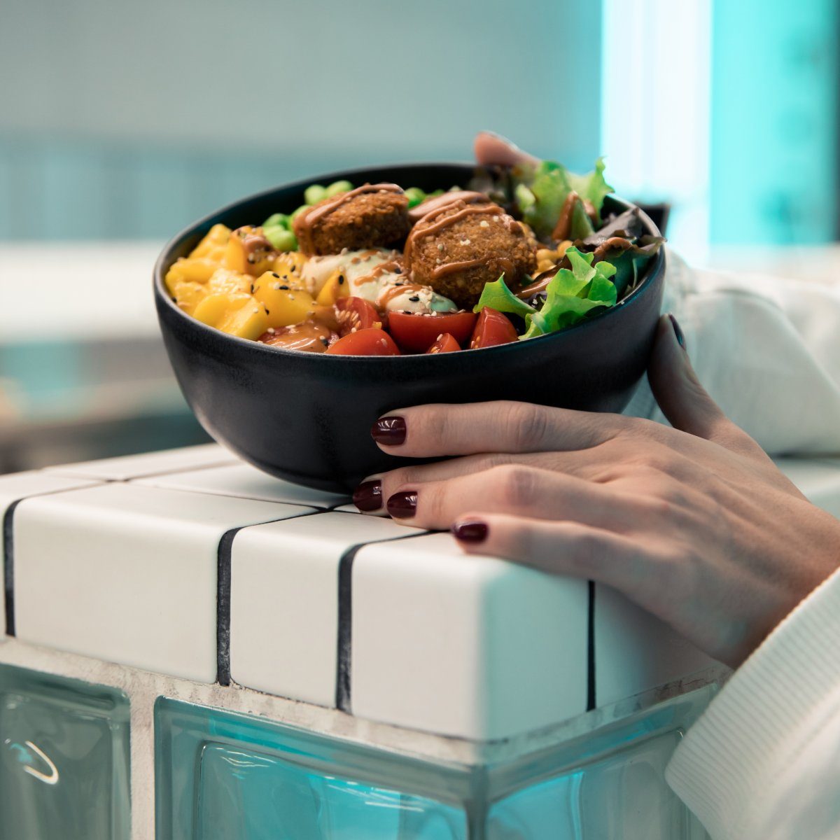 Weibliche Hand zeigt bunte, gesunde Fitnessbowl im King Kong Club Salzburg.