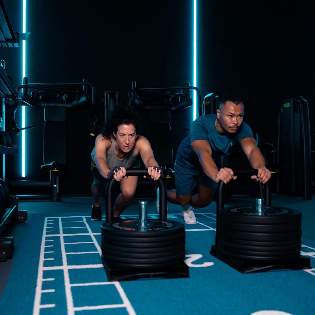 Mann und Frau machen HIIT Intervall Training mit Gewichten im King Kong Club Salzburg.